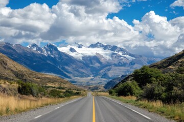 Naklejka premium Scenic highway vanishing point towards snow-capped mountains under a partly cloudy sky. (1)