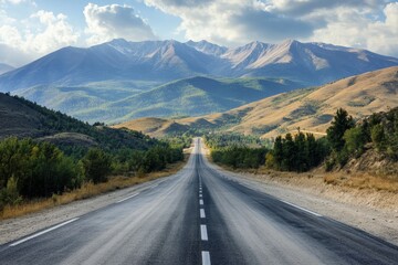 Empty asphalt road leading to majestic mountains under a partly cloudy sky.