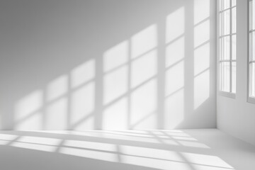 Obraz premium Sunlight streams through large windows into a minimalist white room, casting dramatic shadows on the walls and floor.