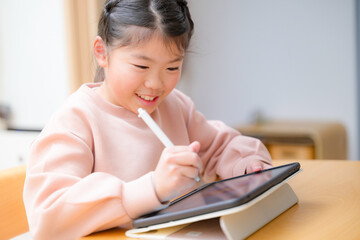 Closeup of a cute smiling kid studying on a tablet with a smiling middle elementary schooler...