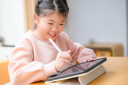 Closeup of a cute smiling kid studying on a tablet with a smiling middle elementary schooler sitting at a desk