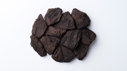 Obraz premium A cluster of dark, textured pieces resembling dried fruit or natural material, arranged on a white surface.