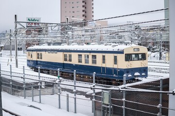 Naklejka premium Japanese Train on Snowy Tracks in a Winter Landscape