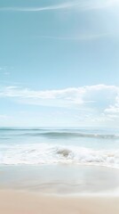 Fototapeta premium Serene beach with soft waves and a clear, sunny sky, creating a perfect atmosphere for relaxation and tranquility.