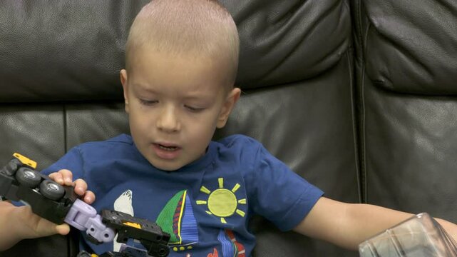 Child unpacking box with robot transformer toy. Face of concentrated little boy taking new toy out of package.