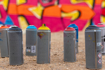 Spray Paint Cans with Colorful Graffiti Wall in the Background