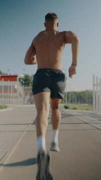 Rear view of a young fit male running outdoors on a bright day, showcasing strength, speed, and determination. Perfect image for themes of fitness, health, and active lifestyle.