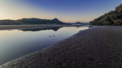 Fototapeta premium Tranquil estuary at low tide. Calm water reflects the hills. Nature's beauty. OPOUTERE, COROMANDEL PENINSULA, NEW ZEALAND