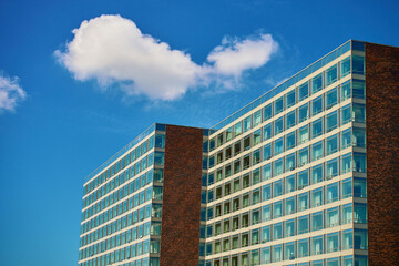 Obraz premium Office building with brick facade and large glass windows under blue sky. Contemporary architectural design, minimalist architecture