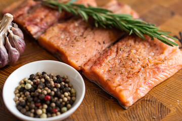 Fillet of red fish with rosemary for steaks on cutting board next to jar with spices. Top view