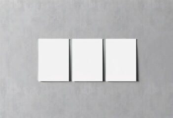 Three crisp white vertical poster or business card mockups standing upright on a gray concrete wall