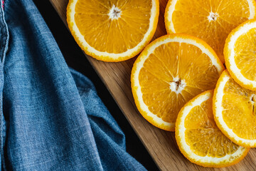 Sliced oranges fruit near denim textile on wooden board. Orange juicy fruit, citrus minimal concept