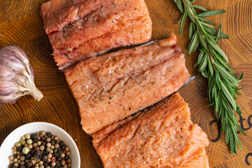 Fillet of red fish with rosemary for steaks on cutting board next to jar with spices. Top view