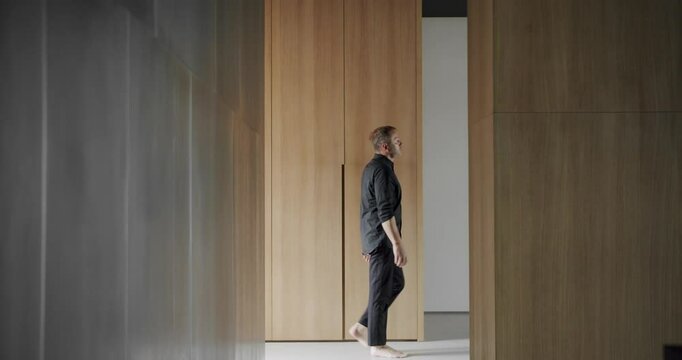 Modern contemporary Minimalist living room with wooden wall. Man goes into the house. Luxury Modern House Interior. Minimalist Home Interior. Cozy Modern Furniture Design. Luxury Elegant Room.