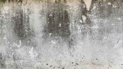 Old gray cement wall texture with black stains, Textured color on cement background. Old concrete wall with cracked flaking paint. The white painted wall surface has scratches and peeling paint.