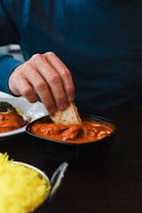 Man dipping his naan bread into Butter Chicken dish in a restaurant in Australia