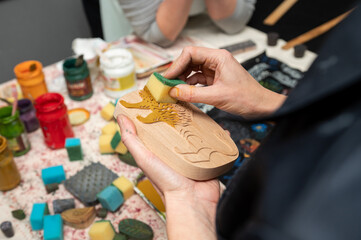 Hands crafting with wooden stamp and sponges in creative workshop