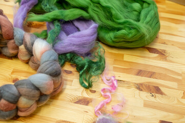 Assorted colorful wool roving and yarn on wooden surface for craft projects