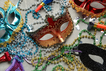 Beautiful carnival masks with party horns, confetti and decor on grey background. Top view