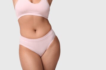 Beautiful young African-American body positive woman on grey background, closeup
