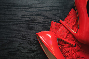 red stiletto heels and stockings lie on a black wooden table