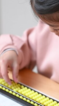 そろばん(珠算)をする小学生のクローズアップ　顔無しの手元のクローズアップの縦動画