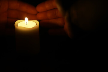 Hands Protecting Candle Flame in Dark Environment, Symbolizing Peace and Serenity
