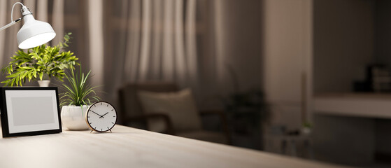 A wooden table featuring decor in a cozy living room at night, softly illuminated by a table lamp.