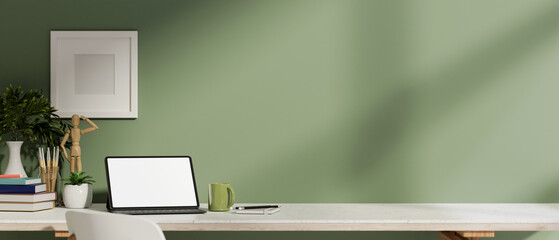 A digital tablet with a white screen mockup and decor on a table against a green wall in a room.