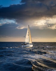 Sailing yacht in the sea at sunset. Dramatic cloudscape.