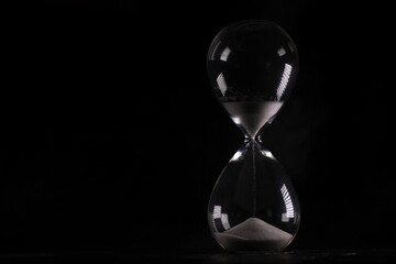 Elegant Hourglass Against Black Background, Time Concept with Sand Flowing in Glass Timer
