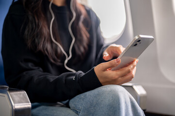 A close-up of a female passenger using her smartphone during the flight.