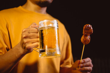A man's hand lifts a beer glass in the quiet aftermath of a night party, capturing a solitary moment of reflection under dim lights and the lingering echo of celebration.