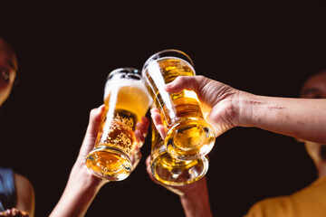 A man's and woman's hands raise beer glasses group in a lively night party, surrounded by family...