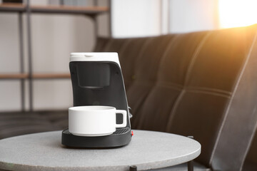 Coffee machine with cup on table in office, closeup