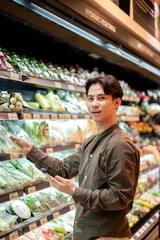 A man selecting vegetables from a shelf while grocery shopping at a supermarket or grocery store.