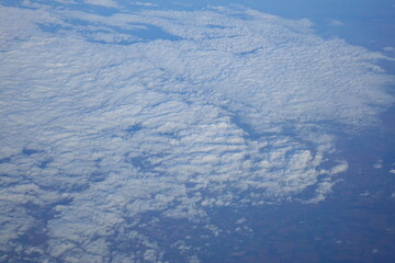 White clouds drift across the stratosphere against a blue sky. A few clouds dot the otherwise brilliant and pure sky. As if gazing up at a picturesque day, the scene is calm and tranquil.