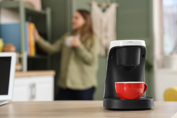 Coffee machine with cup on desk in office, closeup