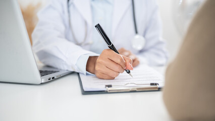 A close-up of a doctor filling out a medical form while examining a patient.