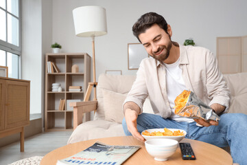 Man eating tasty nachos while watching TV at home