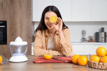 Young woman making tasty orange juice in kitchen