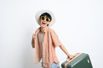 Joyful man wearing summer outfit and sunglasses posing with a suitcase ready for upcoming trip