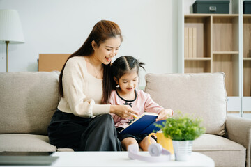 Cheerful mother and daughter sharing quality time on a couch, smiling and using a smartphone...