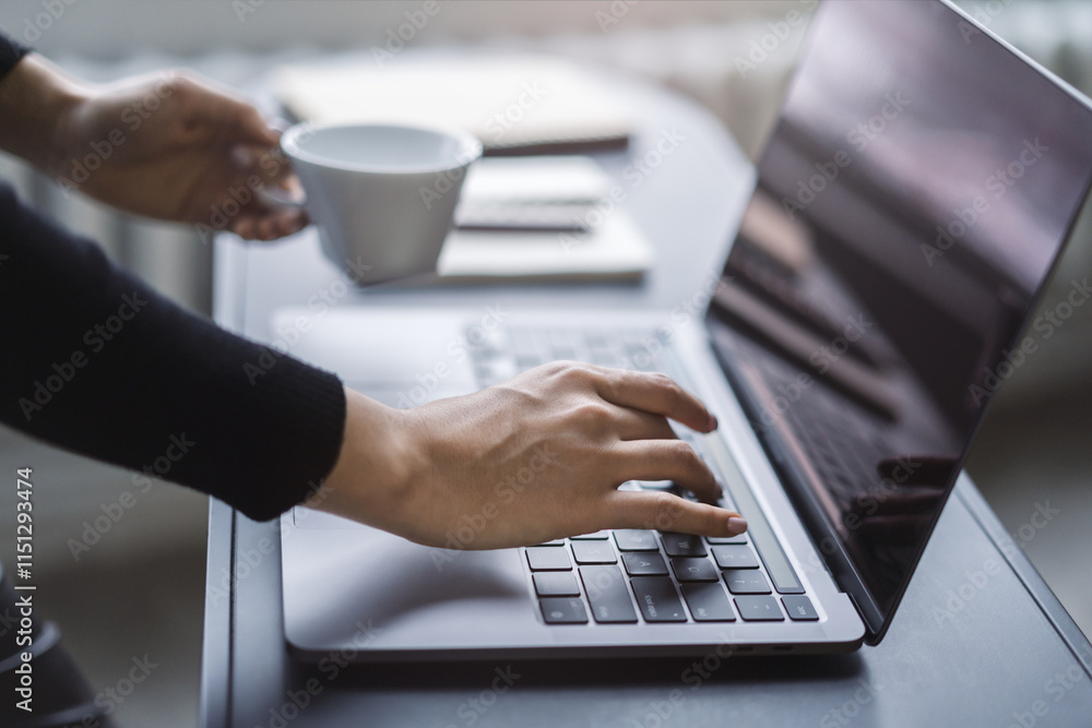 Poster Female hands in sharp focus typing on a modern laptop keyboard, office environment in soft blur behind