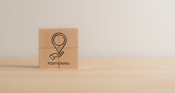 Positioning, marketing concept. Wooden blocks with a location pin and hand icon representing concept of positioning, marketing strategy. Create brand’s unique value proposition. STP marketing model.