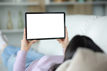 Woman on a couch using tablet showing blank screen
