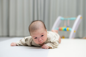 Newborn baby lifting head on play mat