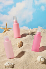 The photo shows three pink spray bottles standing on a white sand side, nestled amongst seashells and pieces of coral. The background is a beach with a blue sky, possibly for a mineral spray promo. © Tuan  Nguyen 
