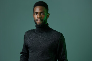 Confident african american man in a stylish turtleneck sweater posing against a vibrant green backdrop