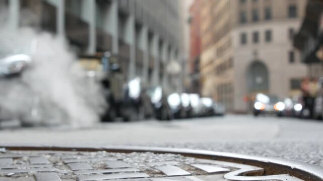 Hot smoke from manhole, Con Edison's Steam system in New York City, United States. Vapor from road on Beaver Street, NYC Downtown Financial District, Lower Manhattan, USA. Urban scene, low angle. Cars